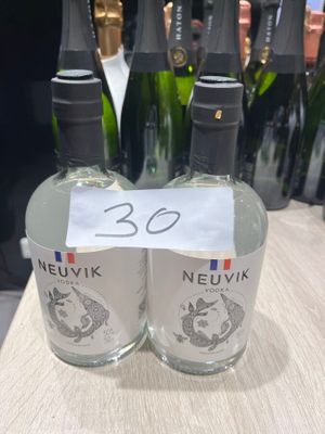 trois bouteilles de vin Neuvix posées sur une table, avec d'autres bouteilles de vin en arrière-plan