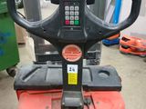 a red forklift with a black handle in a warehouse