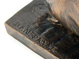 a bronze statue of a bird sitting on top of a wooden block