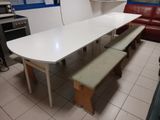 une table blanche avec deux bancs au milieu de la pièce