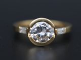 a close up of a gold engagement ring with a white diamond