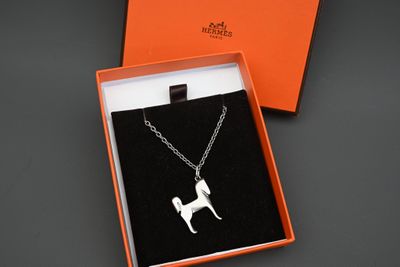une boîte orange contenant un pendentif en forme de chien argenté