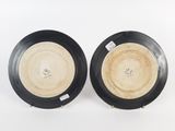 pair of black and white plates with gold rims on a white surface