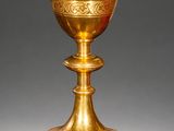 a gold cup with a decorative design on the base