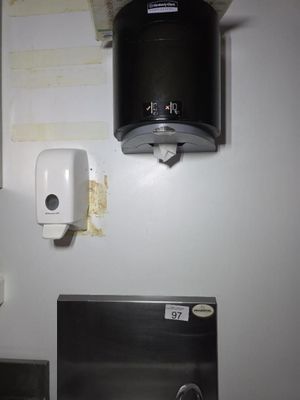 une photo d'une salle de bains avec un lavabo et un distributeur de papier toilette