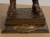 bronze statue of a man holding a baseball bat on top of a wooden base