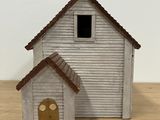 a small white house with a brown roof on a wooden table