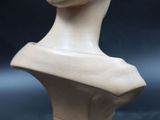 marble bust of a woman on a wooden base on a black background