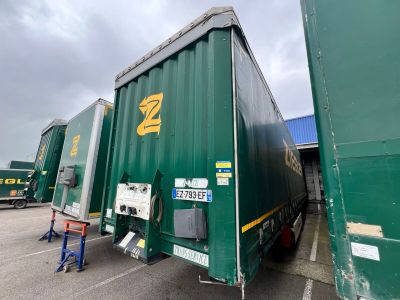 une grande remorque verte garée sur un parking