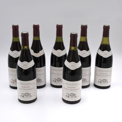 six bottles of wine are lined up in a row on a white surface