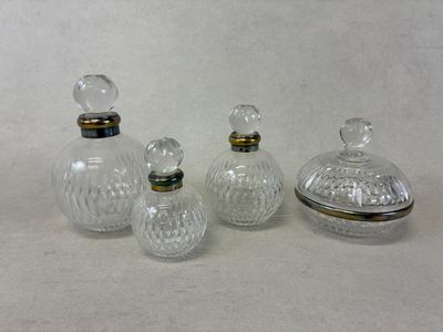 trois bouteilles en verre transparent avec des bouchons argentés, posées sur une surface blanche