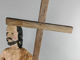 wooden statue of a man carrying a cross on a gray background