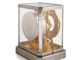 a gold clock inside of a glass case on a white surface