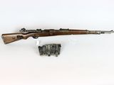a rifle with a wooden barrel and a magazine on a white surface
