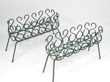 pair of wrought iron garden benches with curved arms and legs