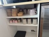 a small refrigerator with a lot of dishes and cups on it