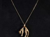 a woman wearing a gold necklace with a kangaroo pendant on it
