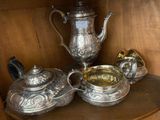 a silver tea set on a shelf in a cabinet
