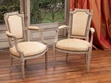 pair of antique chairs in front of a window with a red curtain