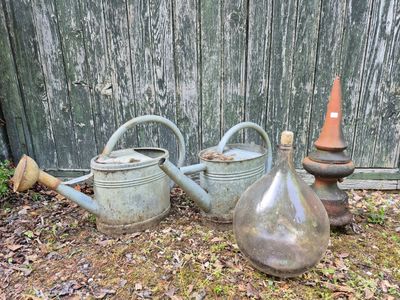 three old watering cans sitting next to each other on the ground