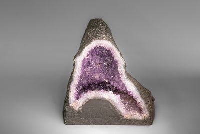 un amethorate présentant des cristaux violets et blancs sur une surface grise