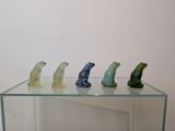 five glass frogs sitting on top of a glass table