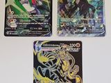 trois cartes à collectionner Pokémon différentes posées sur une surface blanche