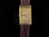 a gold plated wrist watch on a black background