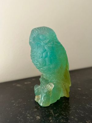 a green bird sitting on top of a black table
