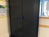 a black cabinet in the corner of a room with boxes on the floor