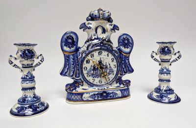 three blue and white vases and a clock on a table