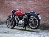 a red and black motorcycle parked next to a brick wall