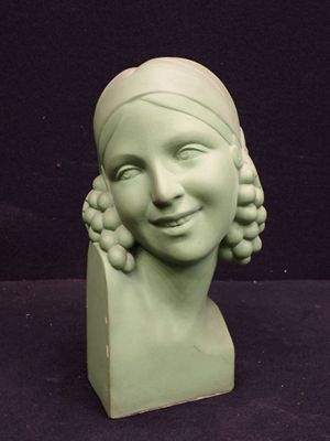 a green statue of a woman with a smile on it ' s face