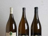 trois bouteilles de vin sont alignées sur une table en bois