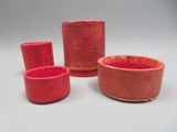 trois vases rouges posés les uns à côté des autres sur une table