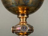 a gold vase with a cross on it on a table