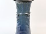 un vase bleu posé sur une surface blanche