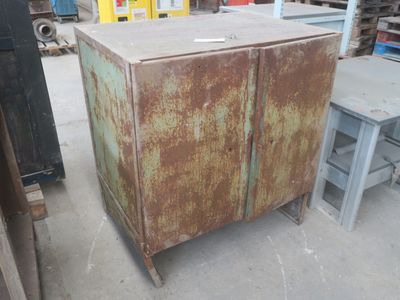 une armoire métallique rouillée dans un entrepôt, avec une table et des chaises