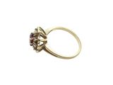 a close up of a gold ring with a red stone