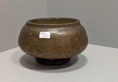 un vase marron posé sur une table, sur lequel est collé un autocollant