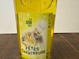 une bouteille de liquide jaune ornée d'un chat, posée sur une table en bois