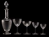 five wine glasses and a decanter on a table