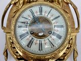 a gold clock that is on a stand with a white background