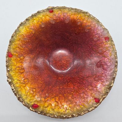 un bol rouge et jaune posé sur une surface blanche