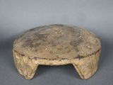 un vieux tabouret en bois posé sur une surface grise