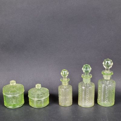 quatre bouteilles en verre vert avec leurs bouchons, posées sur une surface noire
