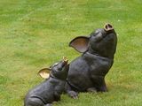 a statue of a pig laying on its back in the grass