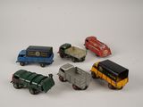 five toy cars and a truck on a white surface