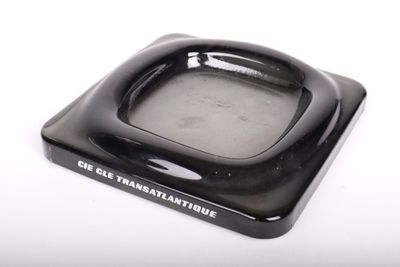 un cendrier noir avec un couvercle blanc posé sur une table blanche