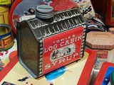 a red and black tin box sitting on a table next to other tin cans